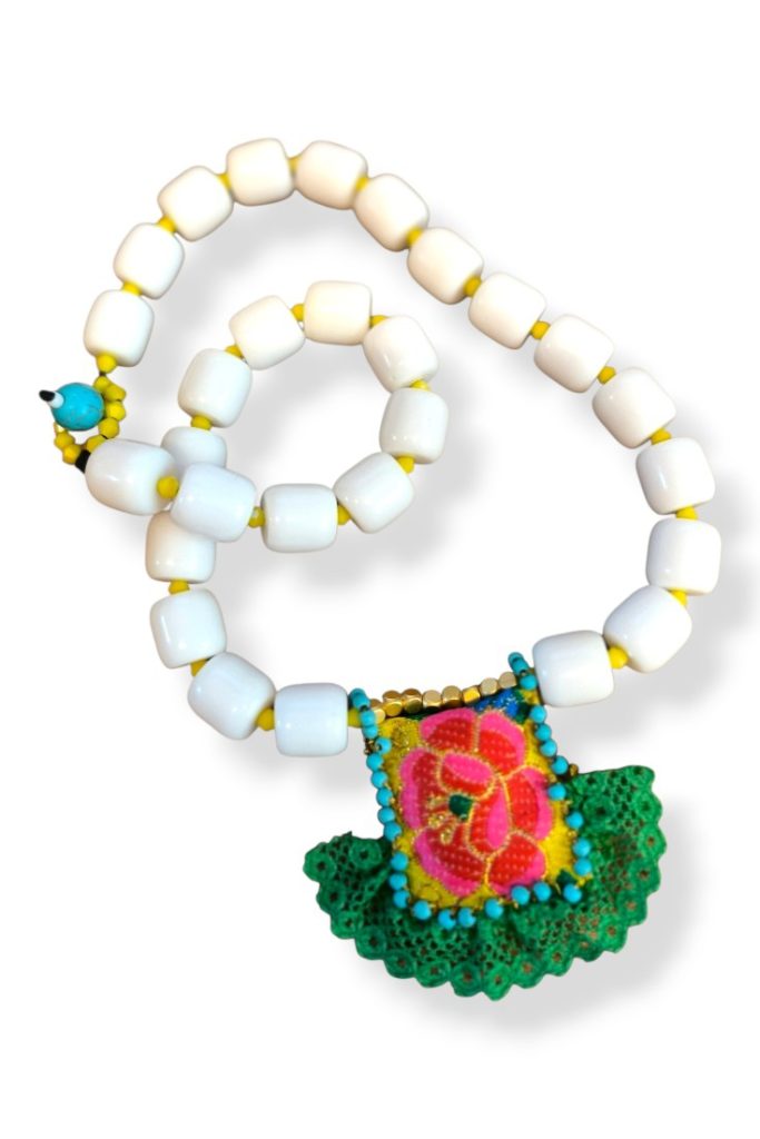 Λευκό κολιέ με ακρυλικές χάντρες και χειροποίητο υφασμάτινο φυλαχτό με floral μοτίβο σε boho στυλ